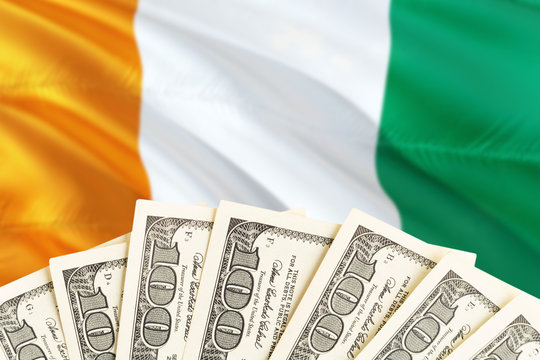 Cote D'Ivoire economy concept. Dollar banknotes on the side of national flag with waving background. Financial theme. - Powered by Adobe