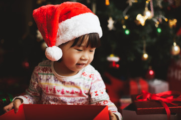 toddler girl getting christmas gift in front of christmas tree