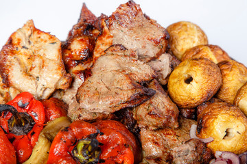 On a platter are meat, mushrooms and vegetables, fried on the grill.