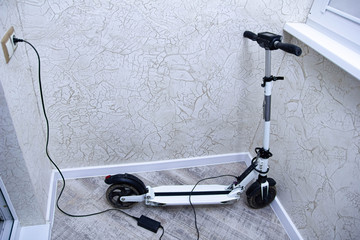 charging the electric scooter battery at home. © velimir
