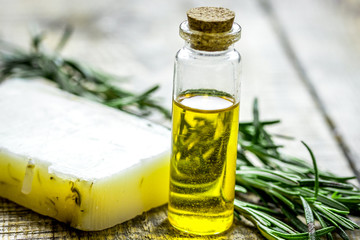 natural cosmetic oil with fresh rosemary and soap on light wooden table background