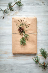 gift wrapping for a book or laptop in craft paper tied with twine rope and decorated with a fir branch with a cone 