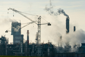 Chemical industry. Environmental pollution by harmful emissions into the atmosphere. Poisonous smoke comes from the big pipes. The factory poisons nature. Silhouette of pipes and smoke. Sunny day.