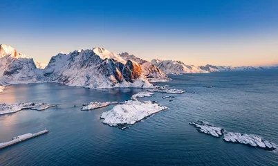 Wall murals Blue Jeans Amazing aerial view of Lofoten Islands nature from drone, winter sunrise snowy scenery of village Reine, Sakrisoy and Hamnoy during beautiful mountain ridge with alpenglow, scene over polar circle.