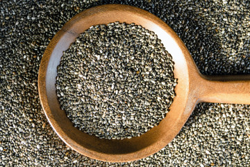 Edible seeds of chia, Salvia hispanica, a flowering plant of the mint family. .Close-up. Chia seeds in a plate of natural olive wood. Product for beauty and health. Proper nutrition. Blurry.