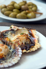 Baked scallops with cheese and spicy sauce. Delicate clam is a real pleasure. Romantic dinner at a Spanish fish restaurant. Mallorca Island, Spain.