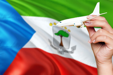 Equatorial Guinea travel concept. Woman holding a miniature plane on national flag background. Holiday and voyage theme with copy space for text. © sezerozger