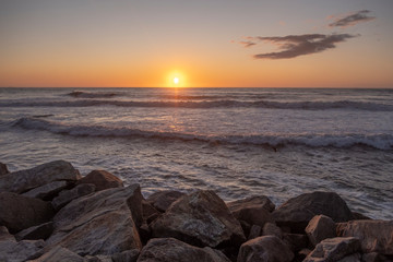 Bonito pôr do sol no mar com ondas e pedras