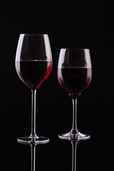  Two glasses with red wine on a black background. Wine on the dark