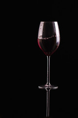 Glass of red wine on black background. Aromatic wine. Strict style. Wine on the dark