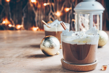 Hot chocolate with whipped cream and marshmallows in a glass mugs on festive background. Selective focus