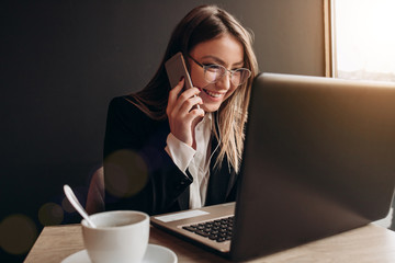 a beautiful girl wearing in office clothes talking on the phone with amazing smile in the cafe
