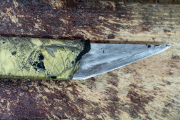 Shoe repair. Old sharp knife lying on a wooden table. Working place of a shoemaker closeup. Wooden background.