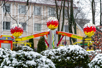 The amusement park is closed. It's winter and very cold. Everything is covered in snow.