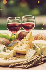 Assortment of cheese on board and two glasses of wine