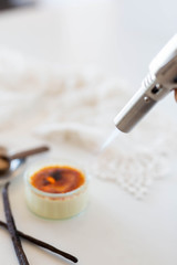 Torching a creme brûlée in white kitchen