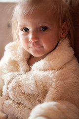 little girl in a white fluffy jacket decorated with lace flowers