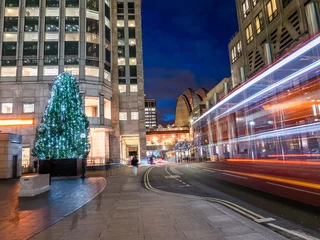 Türaufkleber Traditioneller roter Bus in Bewegung auf der Straße in der Nähe des Stadtplatzes von Canary Wharf, der in den Weihnachtswinterferien in Großbritannien mit einem Baum geschmückt ist © cristianbalate