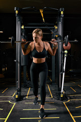 Fototapeta na wymiar Front view of confident young blonde woman doing weight lifting workout Attractive young woman lifting weight looking forward Strong trained body shape arms chest legs.