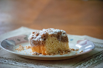 Single piece of coffee crumb cake, streusel, on a plate with a bokeh background with space for copy
