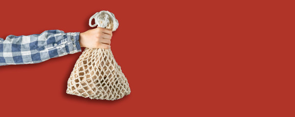 simple abstract image of hand holding a mesh cotton eco bag against the color wall, zero waste recycle