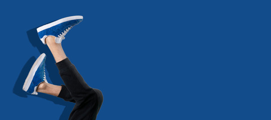 fashion trendy concept, simple legs in sneakers in air against the wall, upside down