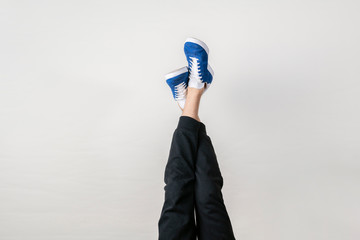 fashion trendy concept, simple legs in sneakers in air against the wall, upside down
