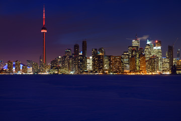 Blue hour from snow covered frozen Lake Ontario of Toronto city skyline lights at night in winter