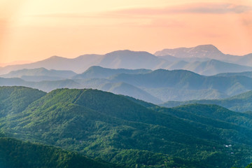 Layers of mountains in the haze during sunset. Beautiful sunset in the hills and mountains. Beautiful sunset in a hilly valley with fog in the lowlands.