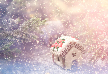 Fototapeta na wymiar Gingerbread house with white icing and branch of christmas tree covered with snow 