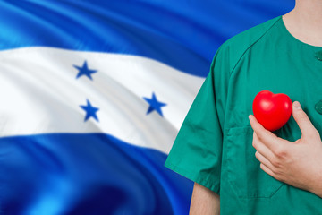 Honduras veterinary clinic concept. Veterinarian is holding plastic heart in green uniform on...