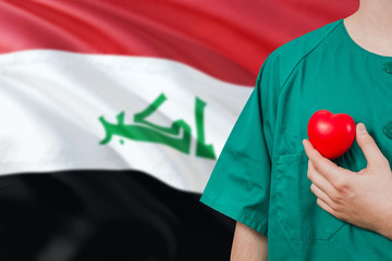 Iraq veterinary clinic concept. Veterinarian is holding plastic heart in green uniform on national...