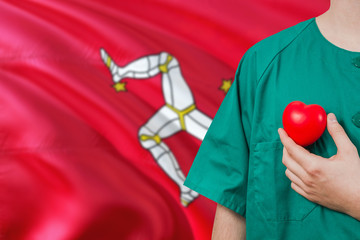 Isle Of Man veterinary clinic concept. Veterinarian is holding plastic heart in green uniform on...