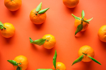 Fresh orange tangerines with leaves, on an orange background, flat lay.