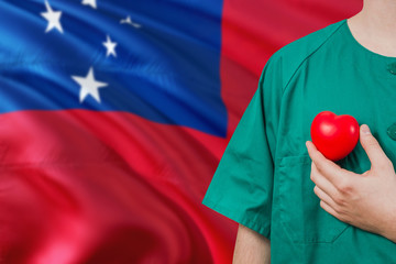 Samoa veterinary clinic concept. Veterinarian is holding plastic heart in green uniform on national...