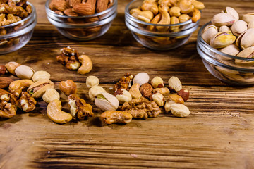 Fototapeta na wymiar Various nuts (almond, cashew, hazelnut, pistachio, walnut) in glass bowls on a wooden table. Vegetarian meal. Healthy eating concept