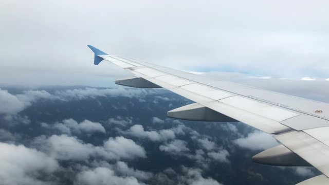 4k Shot of Airplane Wing Flying Over Mountains and Clouds in California