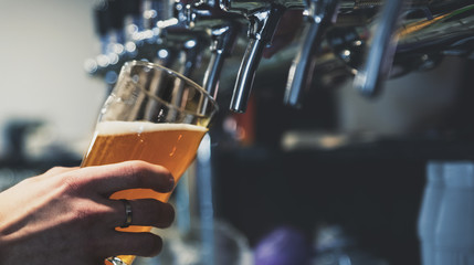 Barkeeper-Hand am Bierzapfhahn, der ein Fassbier in Glas einschenkt, das in einem Restaurant oder einer Kneipe serviert wird