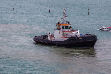 Fototapeta premium Tugboat working in the port of Venice, Italy. Concept: maritime transport, commerce, shipbuilding industry, maritime trade