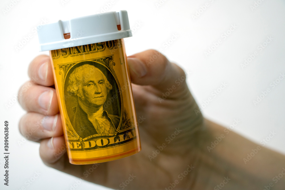 Wall mural Hand holding a pill bottle with dollar bill inside