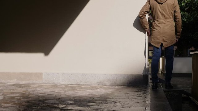 young blind man with his white stick going down the steps