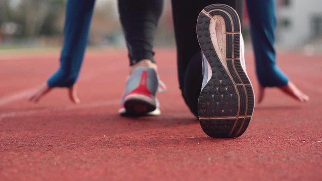 Back view of a young athlete getting ready for the race on a running track .