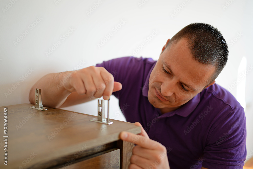 Wall mural handsome man assembles furniture in his apartment