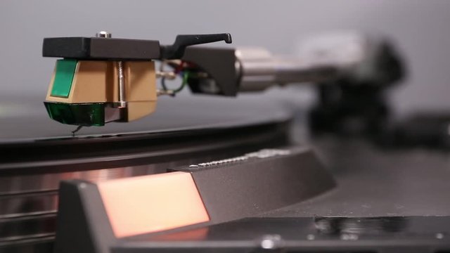 Phono cartridge close up on spinning turntable.