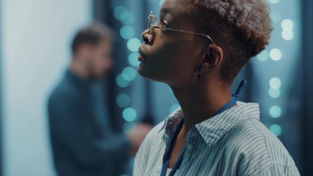 African american woman specialist inspecting visually server cabinet racks, using wireless laptop technologies, coworking with man in database center.
