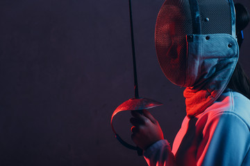 Fencer woman in mask profile portrait with fencing sword.
