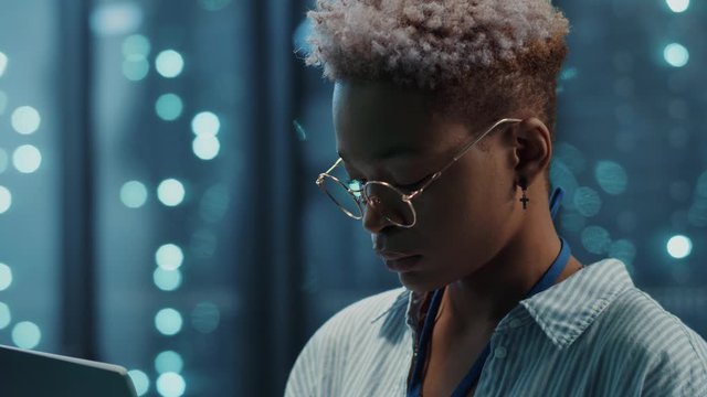 Beautiful african woman IT engineer inspecting a secure server cabinet using modern technology laptop coworking with male technician in data center.
