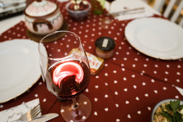 Glass with red wine on festive tablecloth ready for Christmas winter new year holidays