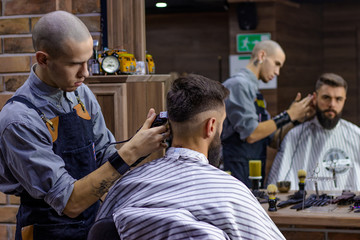 Young bearded man getting haircut by hairdresser at barber shop. Advertising and barber shop...