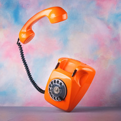 Vintage orange telephone on a bright colorful background